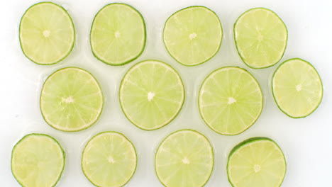 In-slow-motion-water-splashes-pour-water-onto-a-beautiful-juicy-citrus-many-limes-on-a-white-background.-Vegetarian-and-Fructorians.